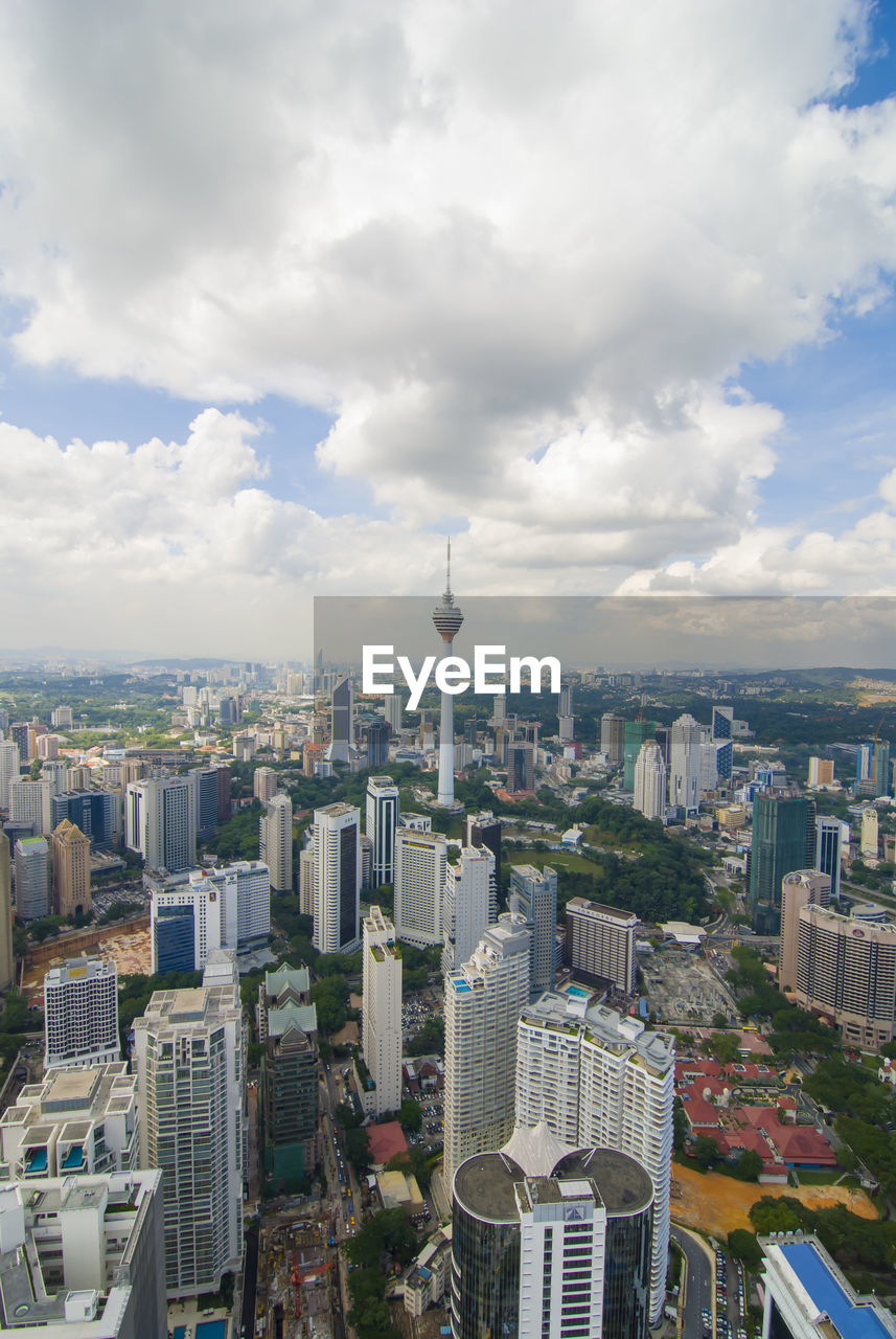 Aerial view of buildings in city against cloudy sky