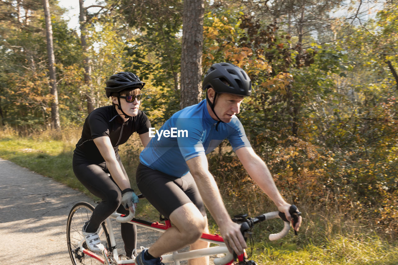 Visually impaired female triathlete training on tandem bicycle with her guide and coach