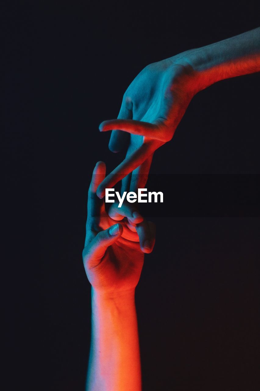 Cropped image of people touching fingers against black background