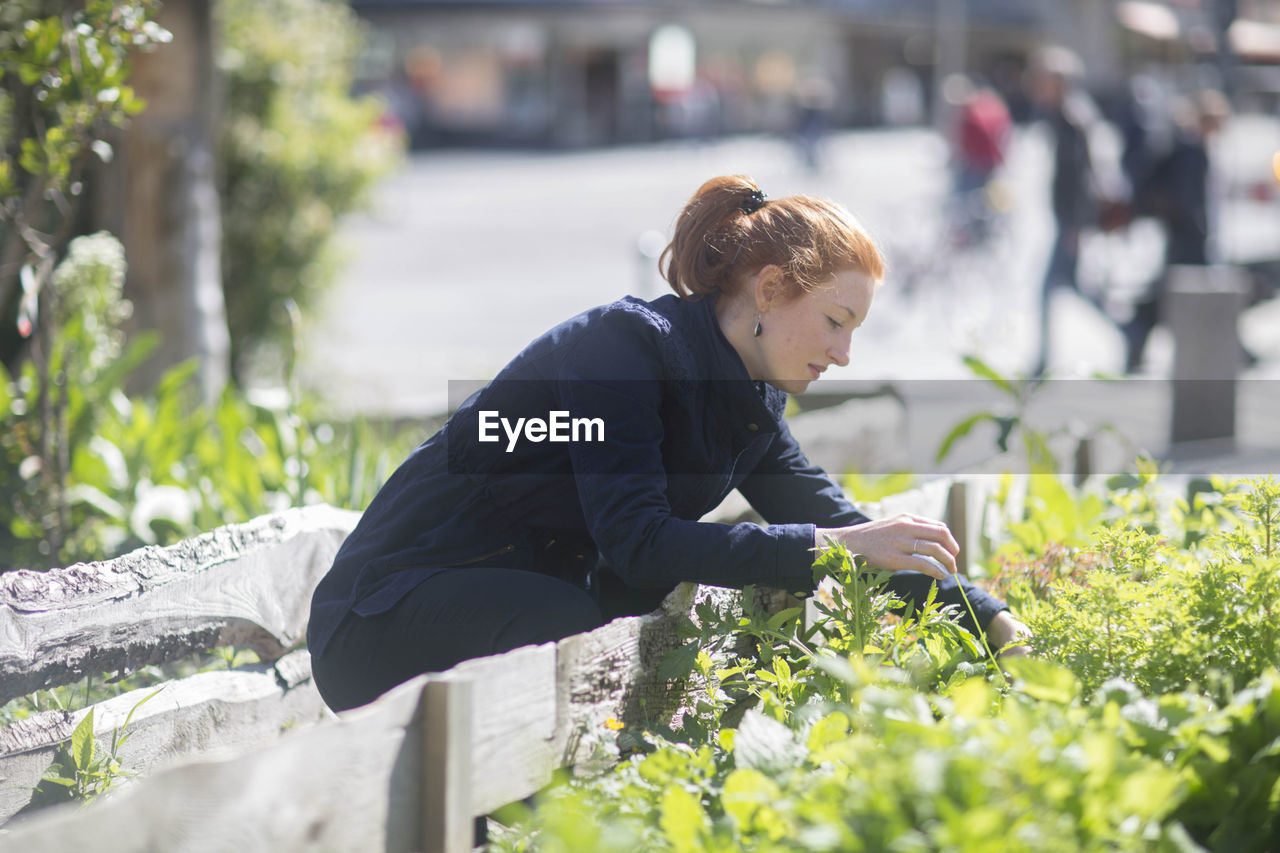 Young woman working in a urbanic garden in a city