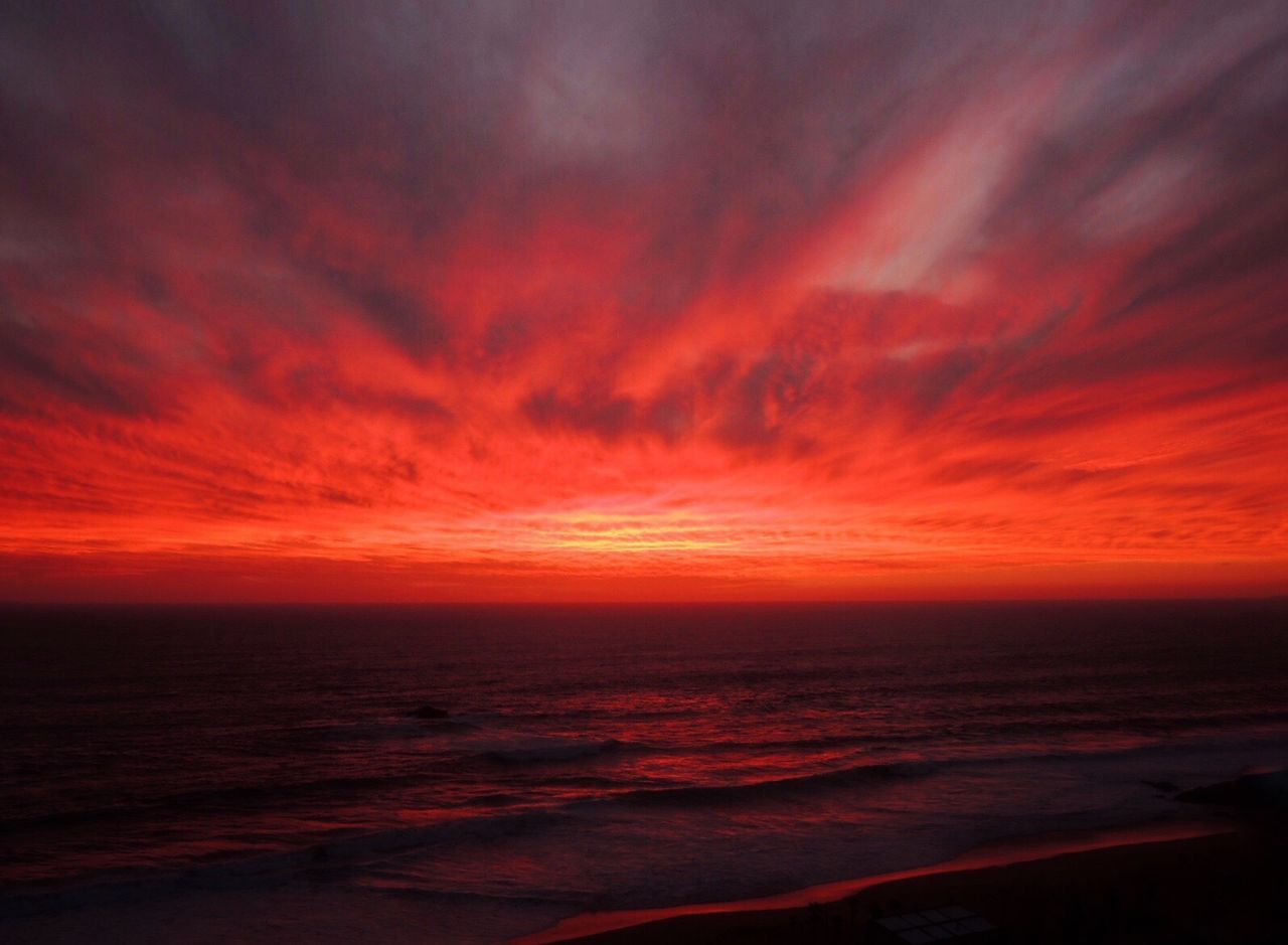 Scenic view of sea against dramatic sky during sunset