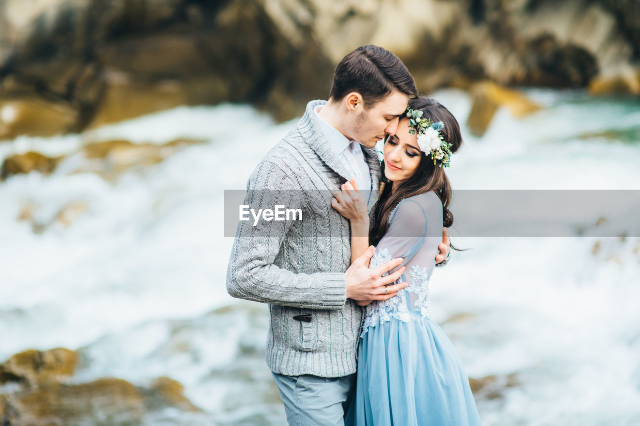 YOUNG COUPLE STANDING AT SHORE