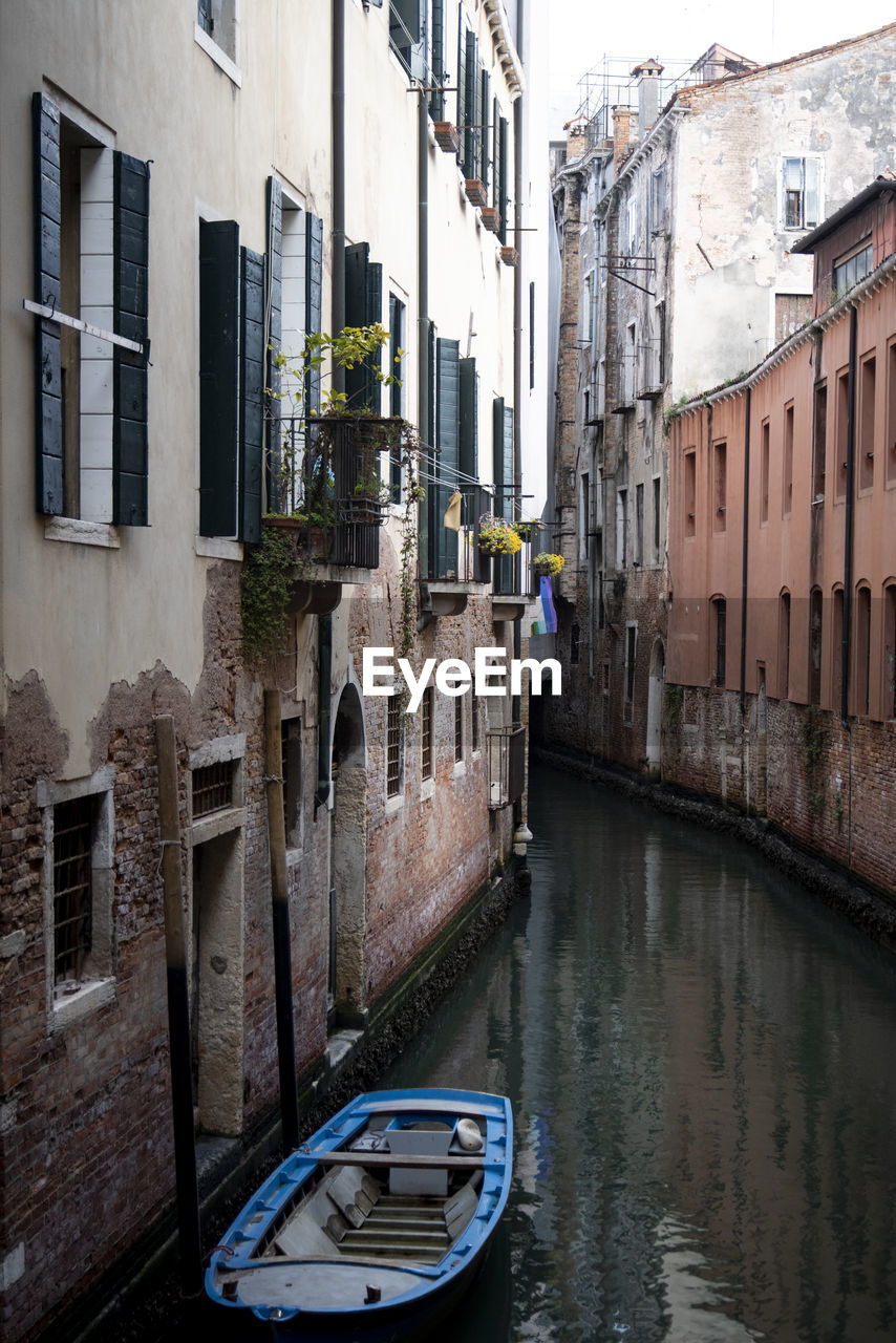 boats in canal amidst buildings