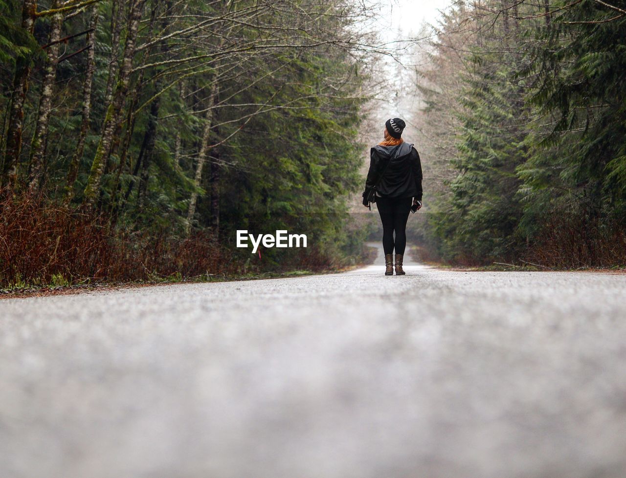 Rear view full length of woman standing on footpath amidst trees