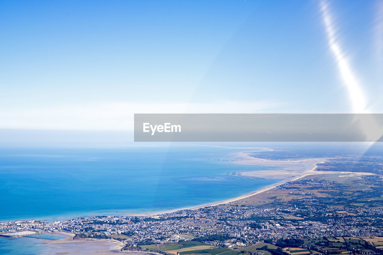 Aerial view of city by sea against sky