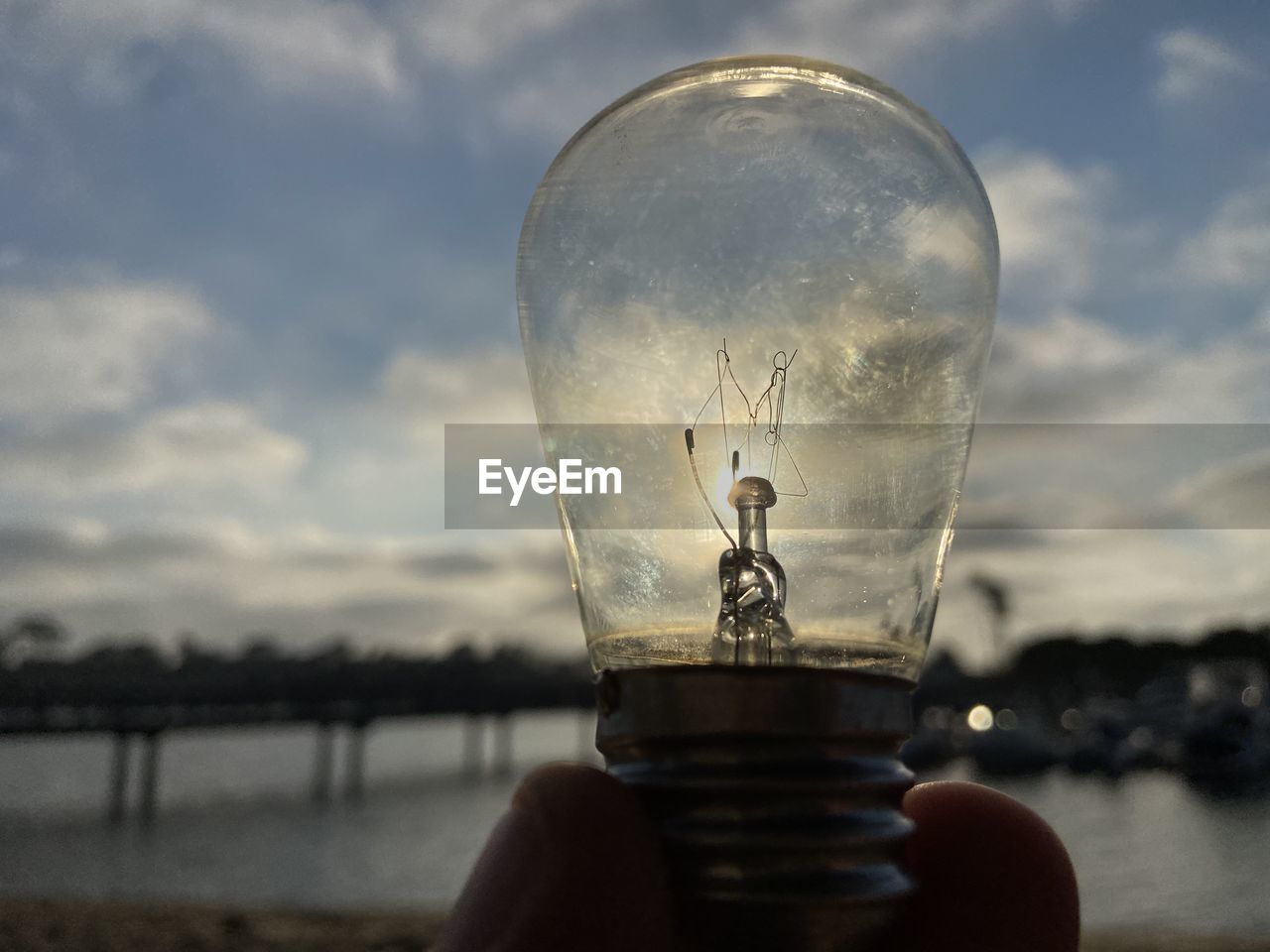 CLOSE-UP OF LIGHT BULB AGAINST CLOUDY SKY