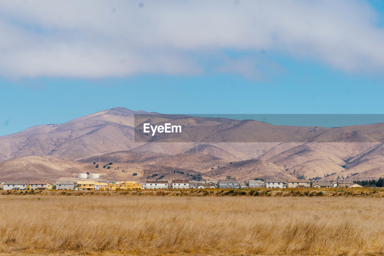 Scenic view of farm field by mountains against sky
