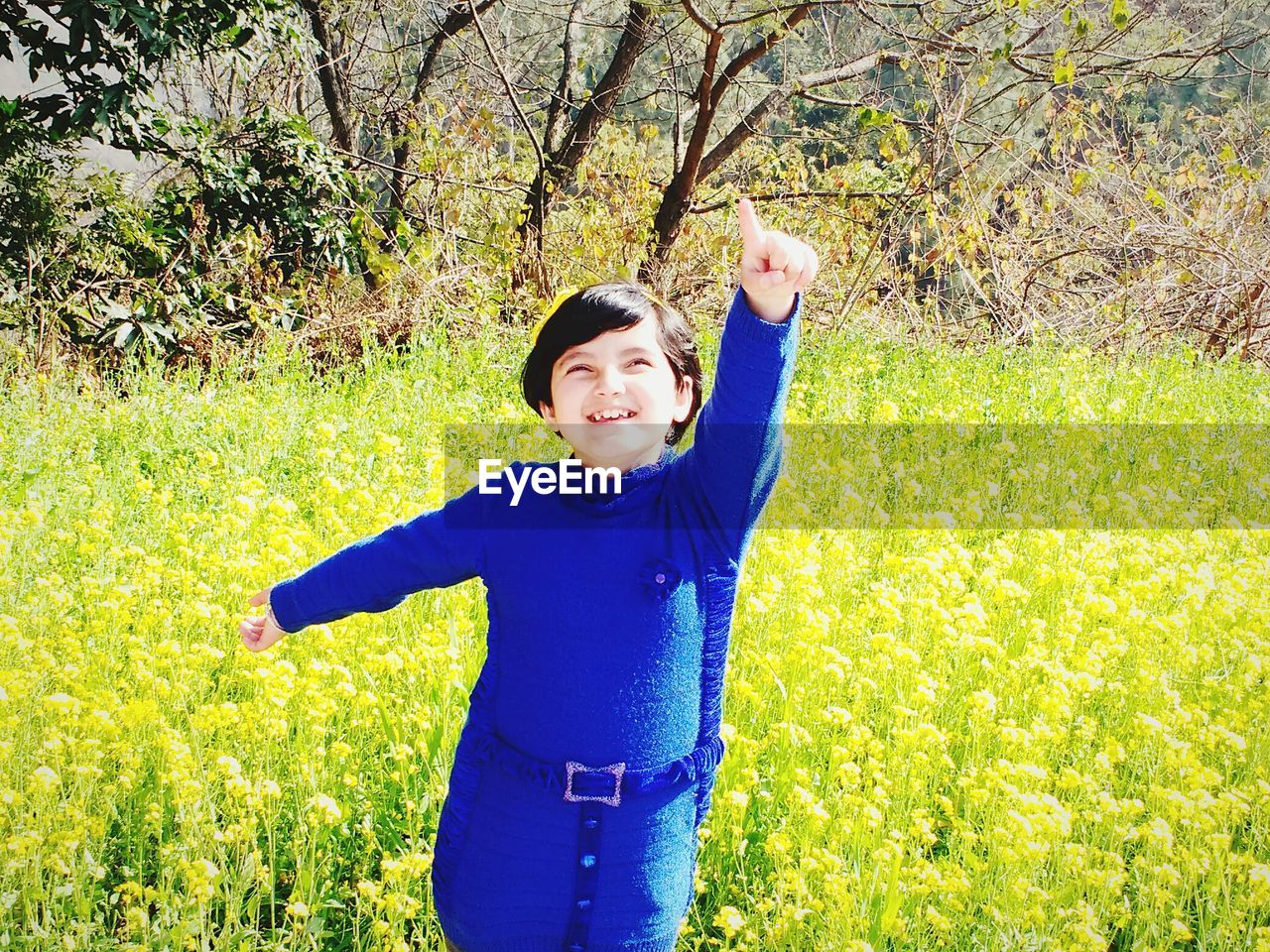 PORTRAIT OF YOUNG WOMAN STANDING ON GRASSY FIELD