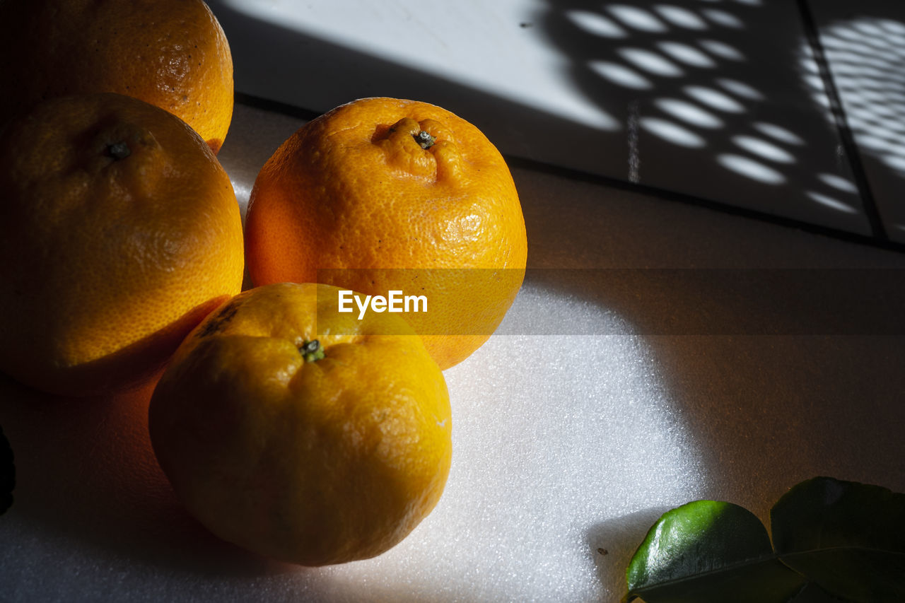 Fresh orange fruits with light and shadow as background