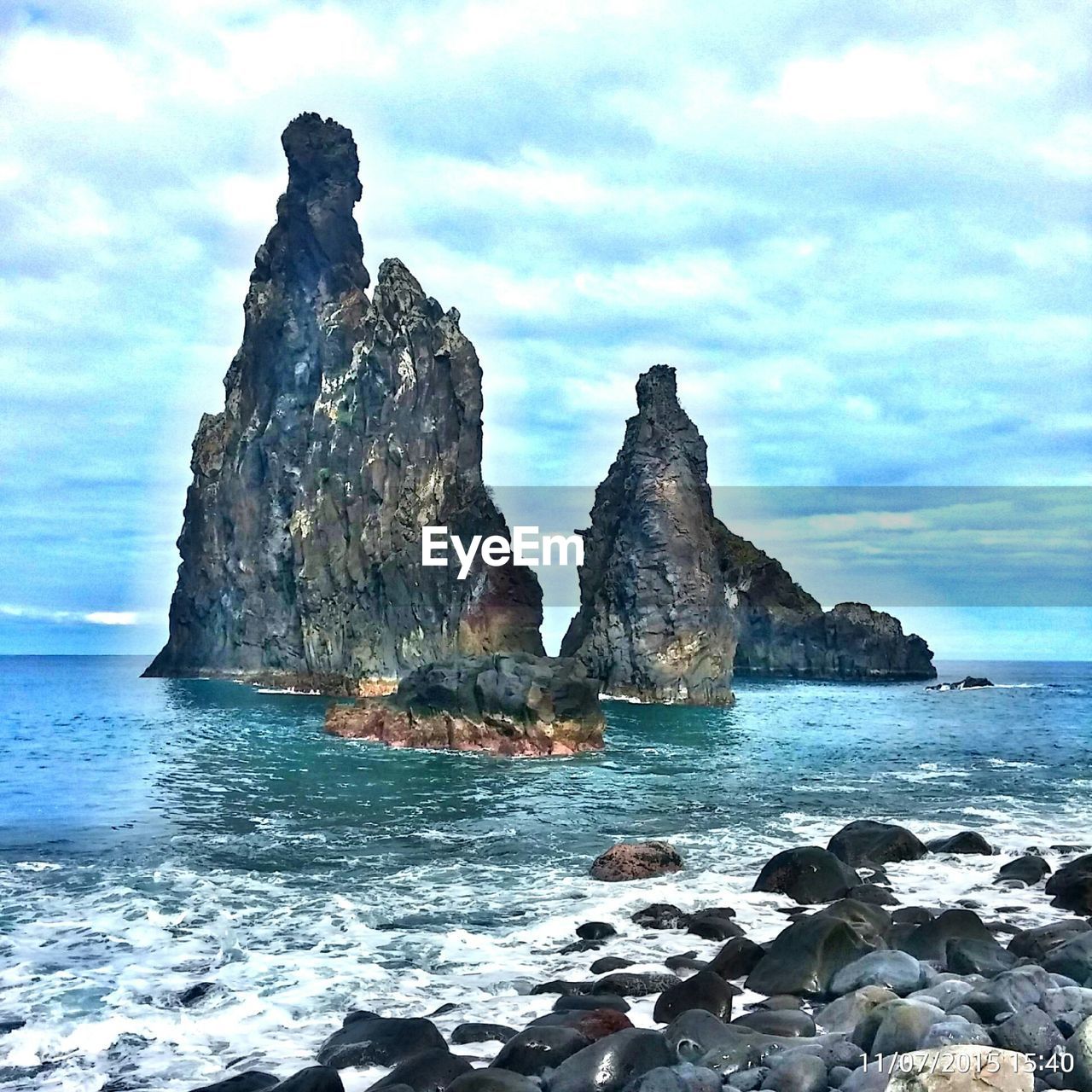 SCENIC VIEW OF SEA AND ROCKS AGAINST CLOUDY SKY