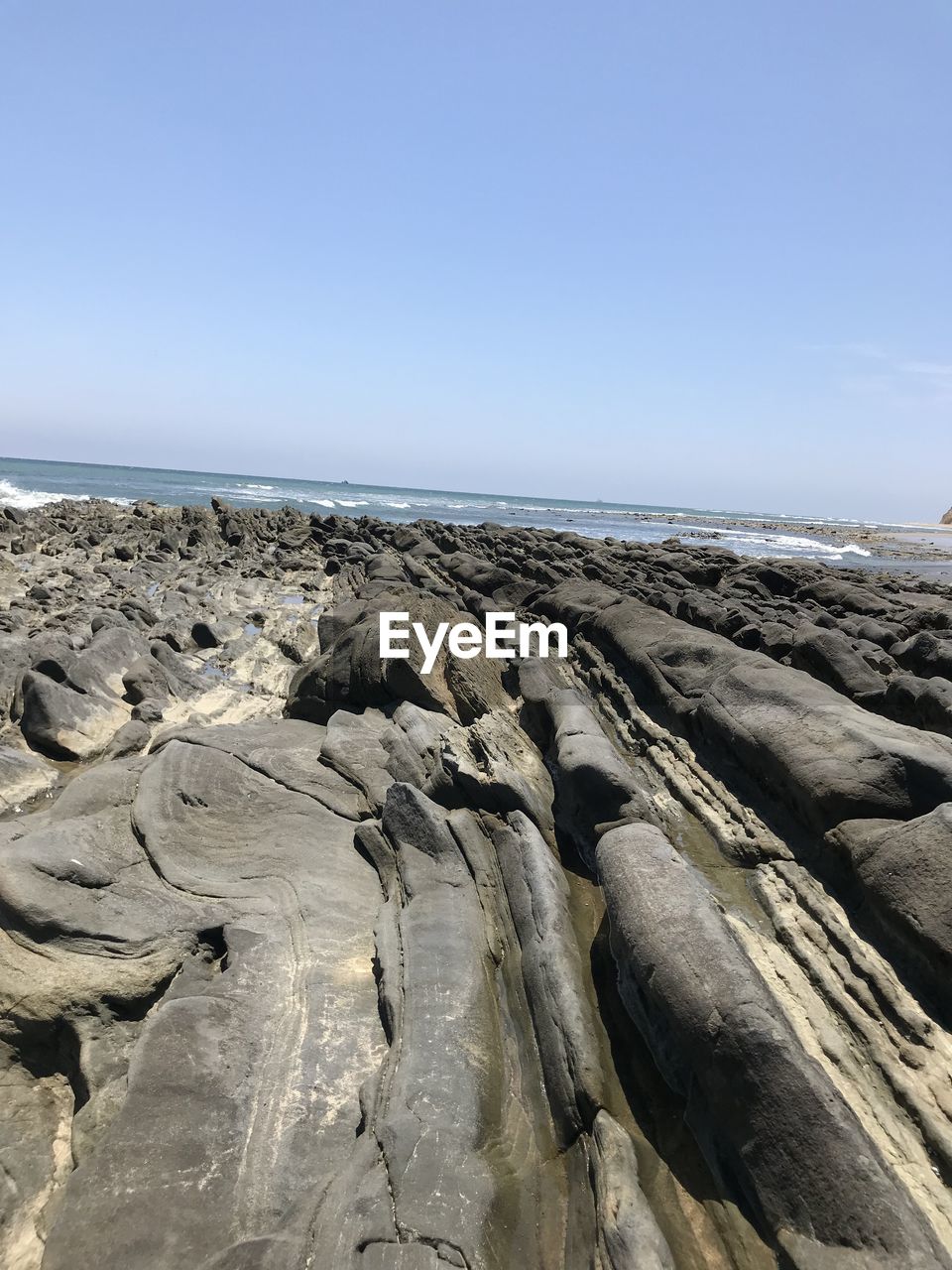 Panoramic view of rocks on beach against clear sky