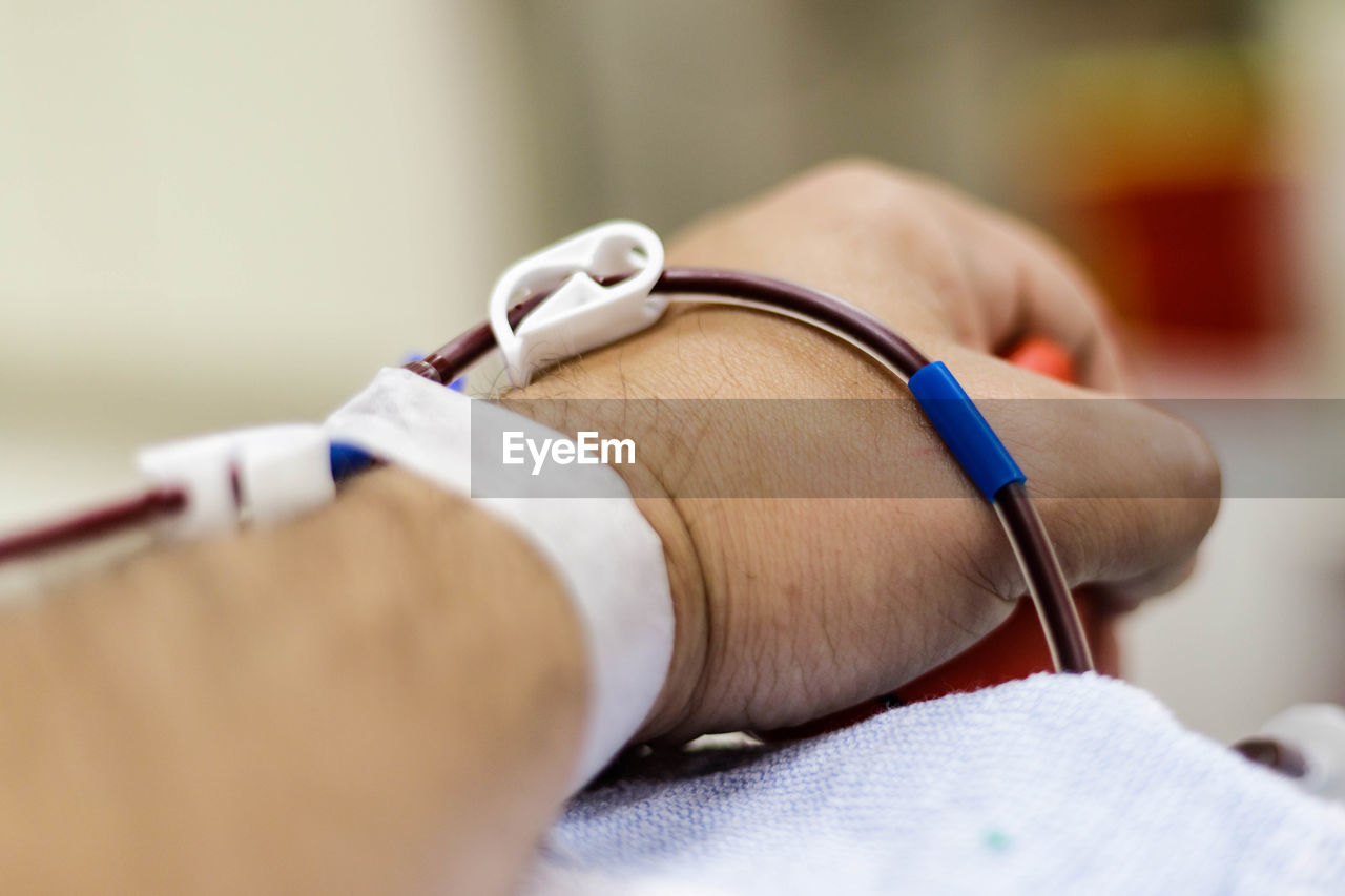 Cropped hand of man with iv drip in hospital