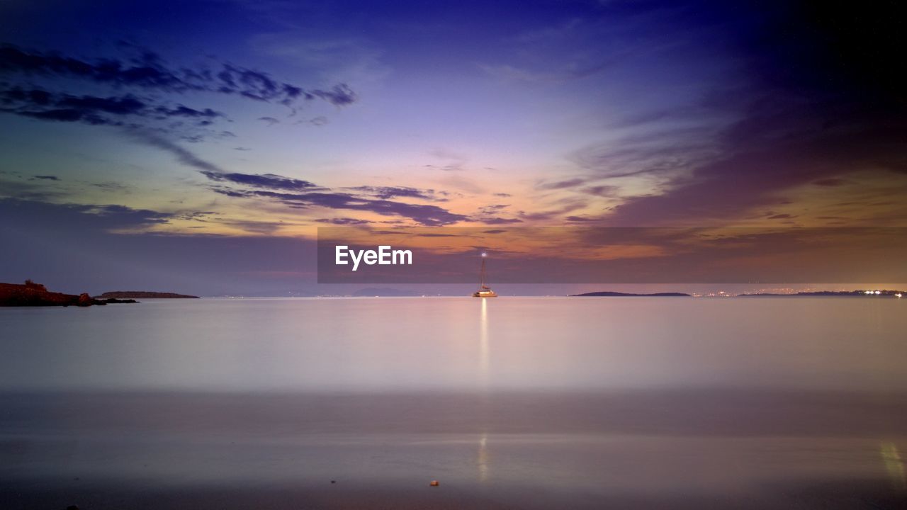 Scenic view of sea against cloudy sky during sunset