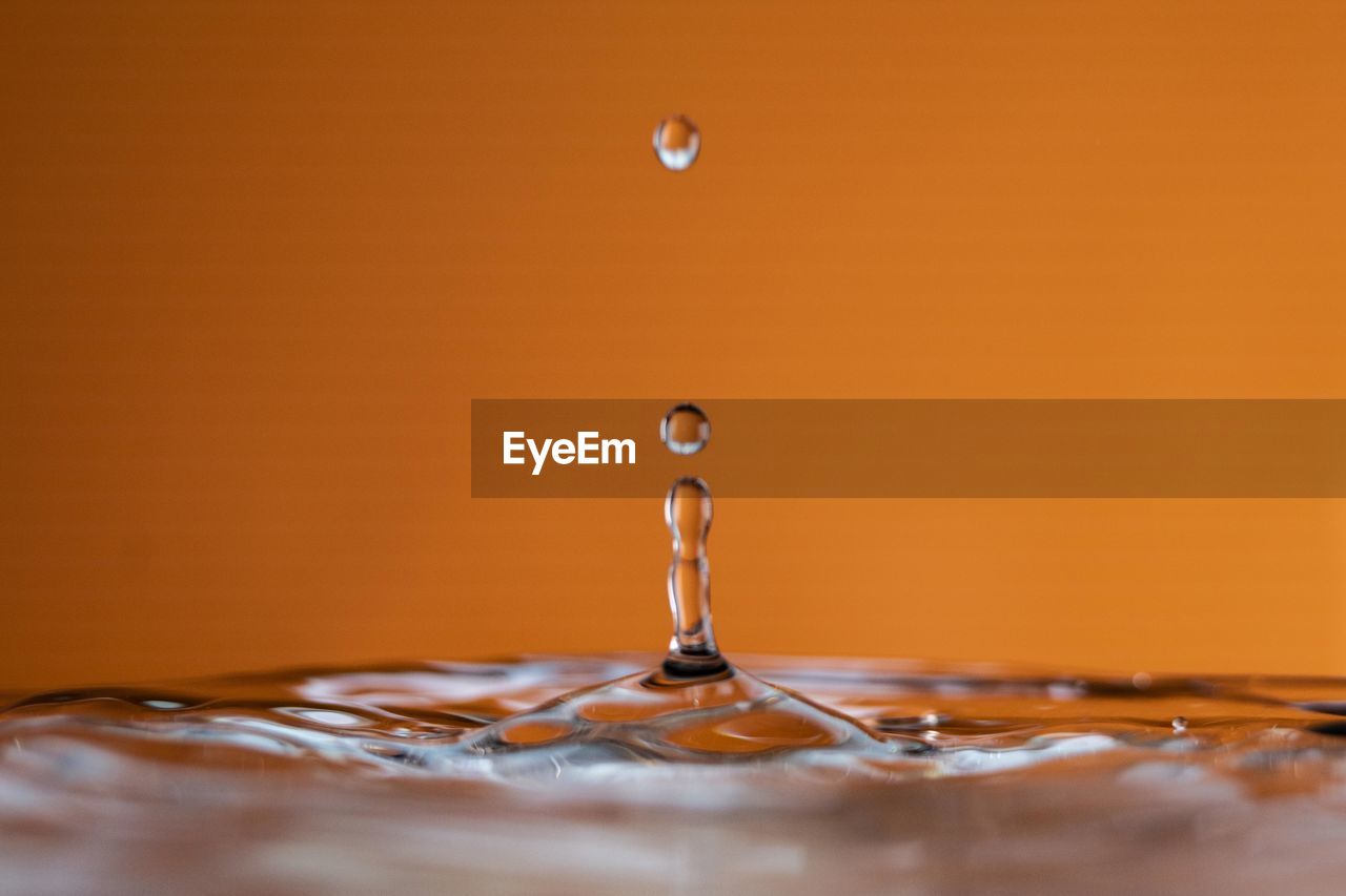 Close-up of water splashing against yellow background