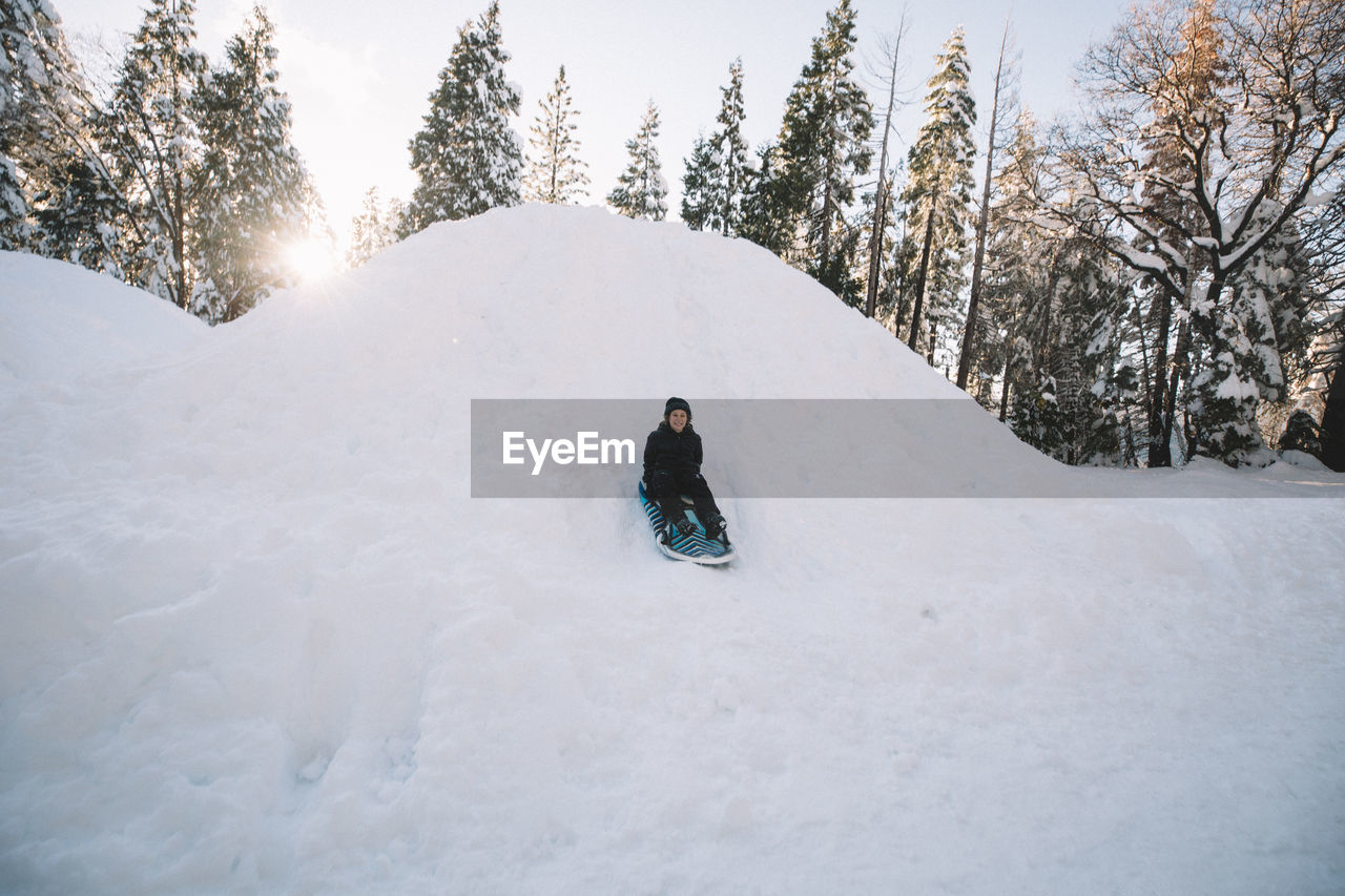 Young boy sledding quickly down a hill.