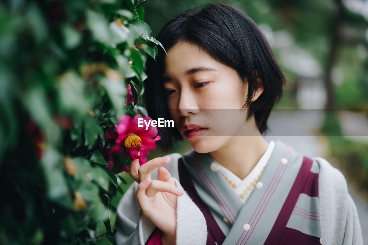 PORTRAIT OF WOMAN WITH PINK FLOWER