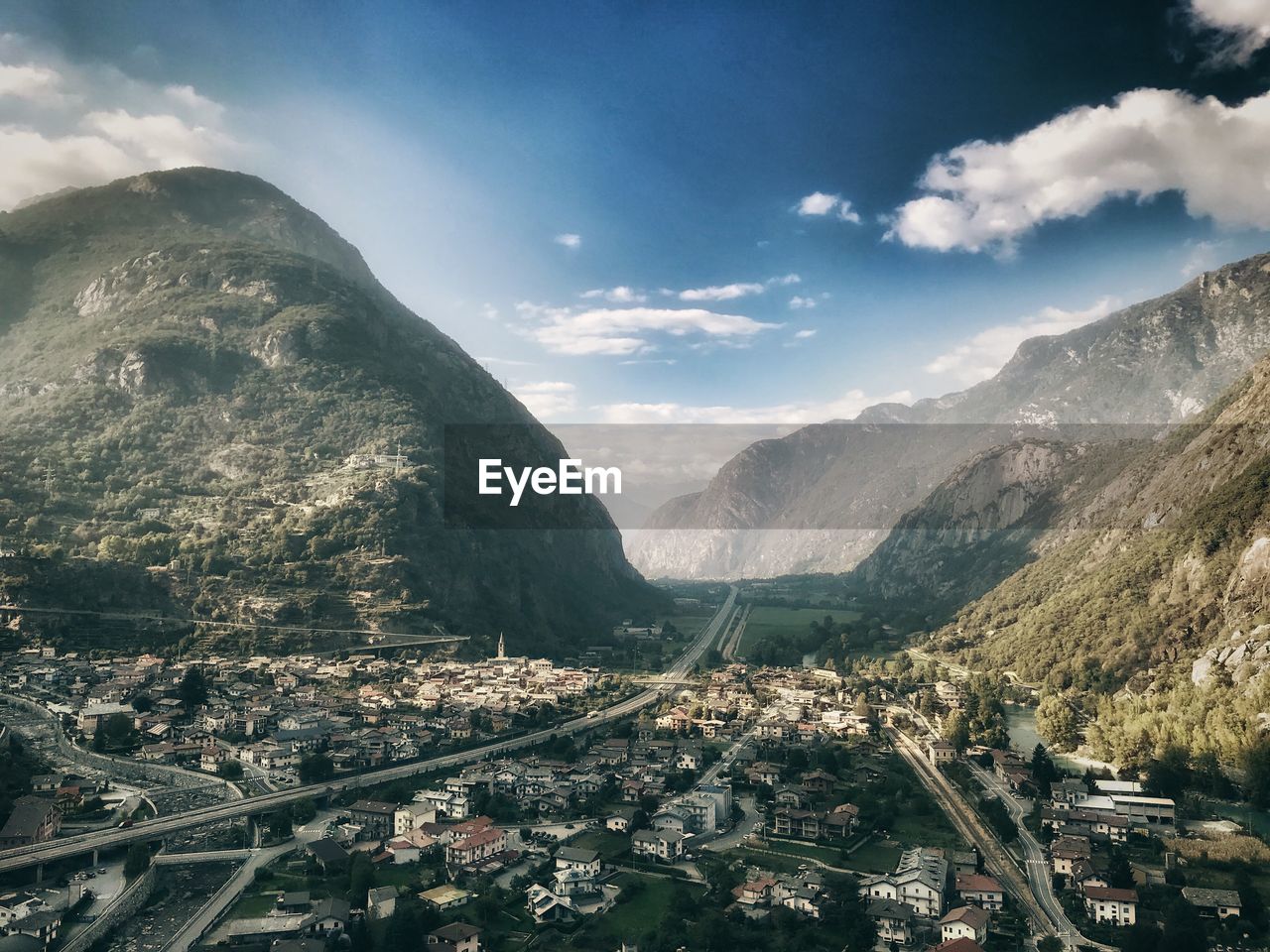 HIGH ANGLE VIEW OF TOWNSCAPE BY MOUNTAINS AGAINST SKY