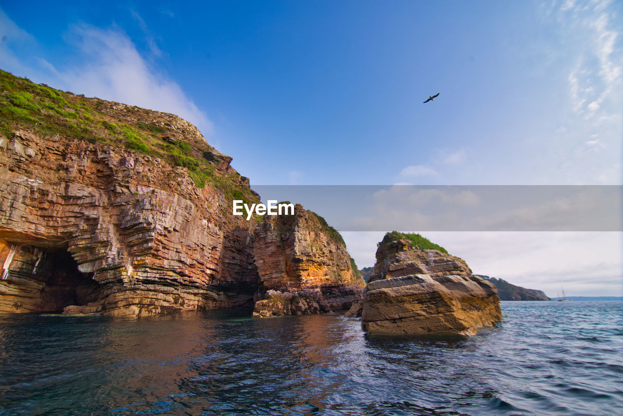 Rock formations by sea against sky