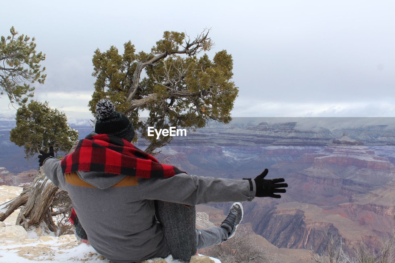 Rear view of woman sitting on mountain during winter