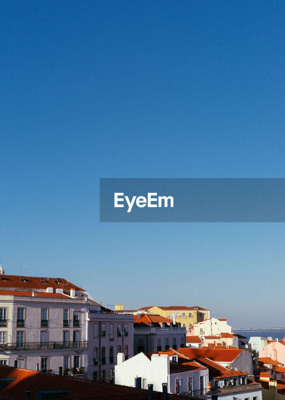 Buildings in city against clear blue sky