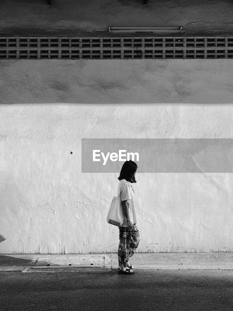 SIDE VIEW OF WOMAN STANDING ON WALL