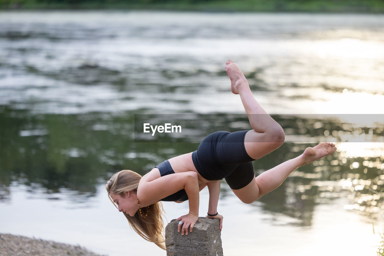 rear view of woman doing yoga on lake