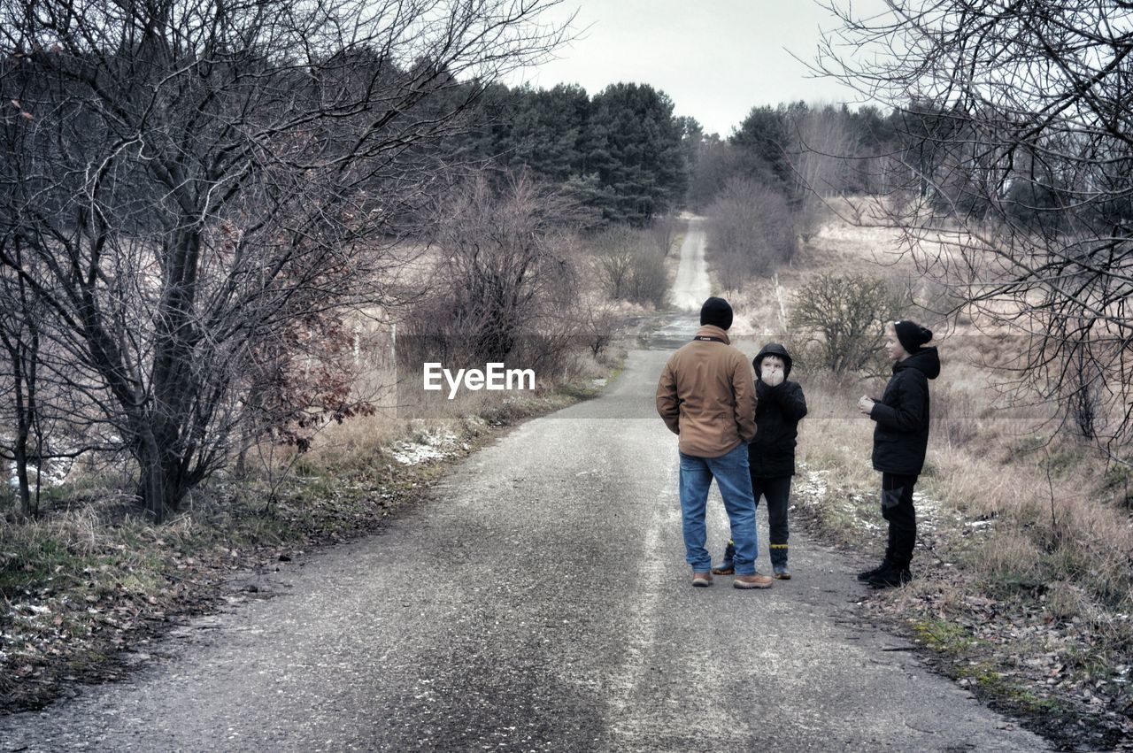 REAR VIEW OF MEN WALKING ON FOOTPATH