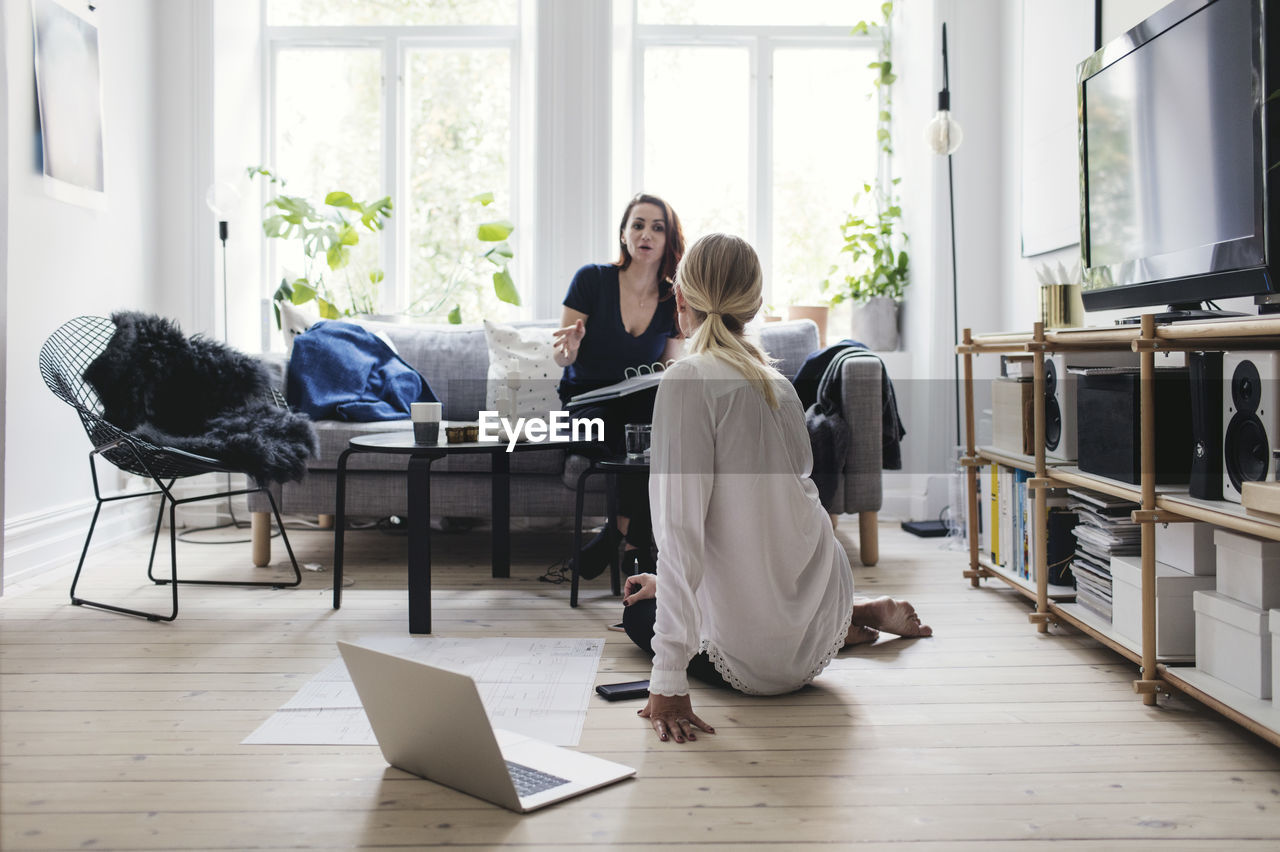 Colleagues discussing while sitting in living room