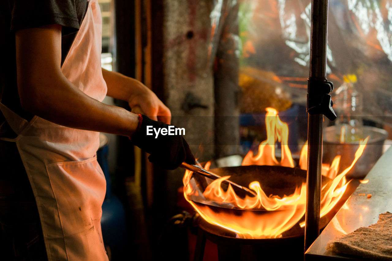 Midsection of chef preparing food in commercial kitchen