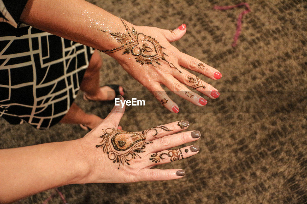 High angle view of female friends showing henna tattoos