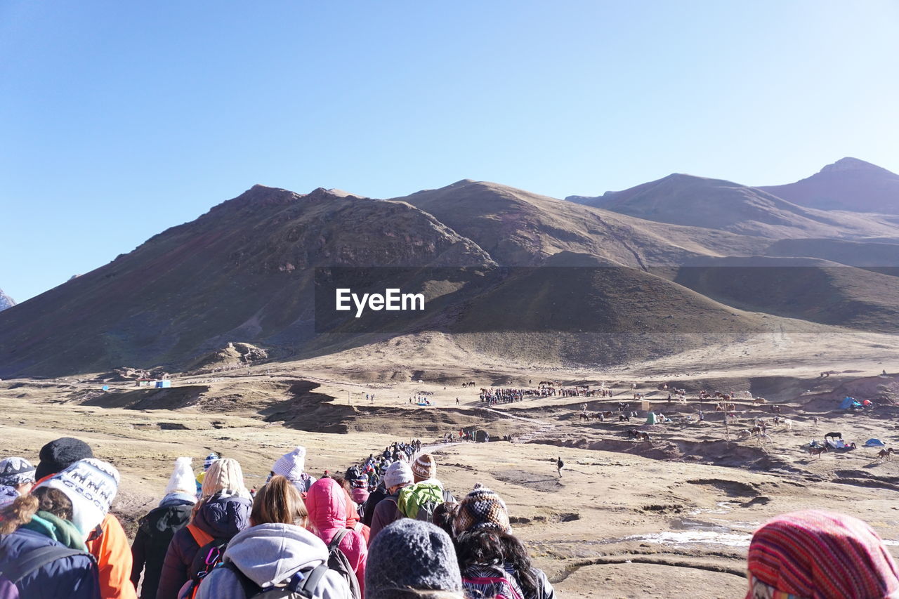 People walking on landscape against mountains