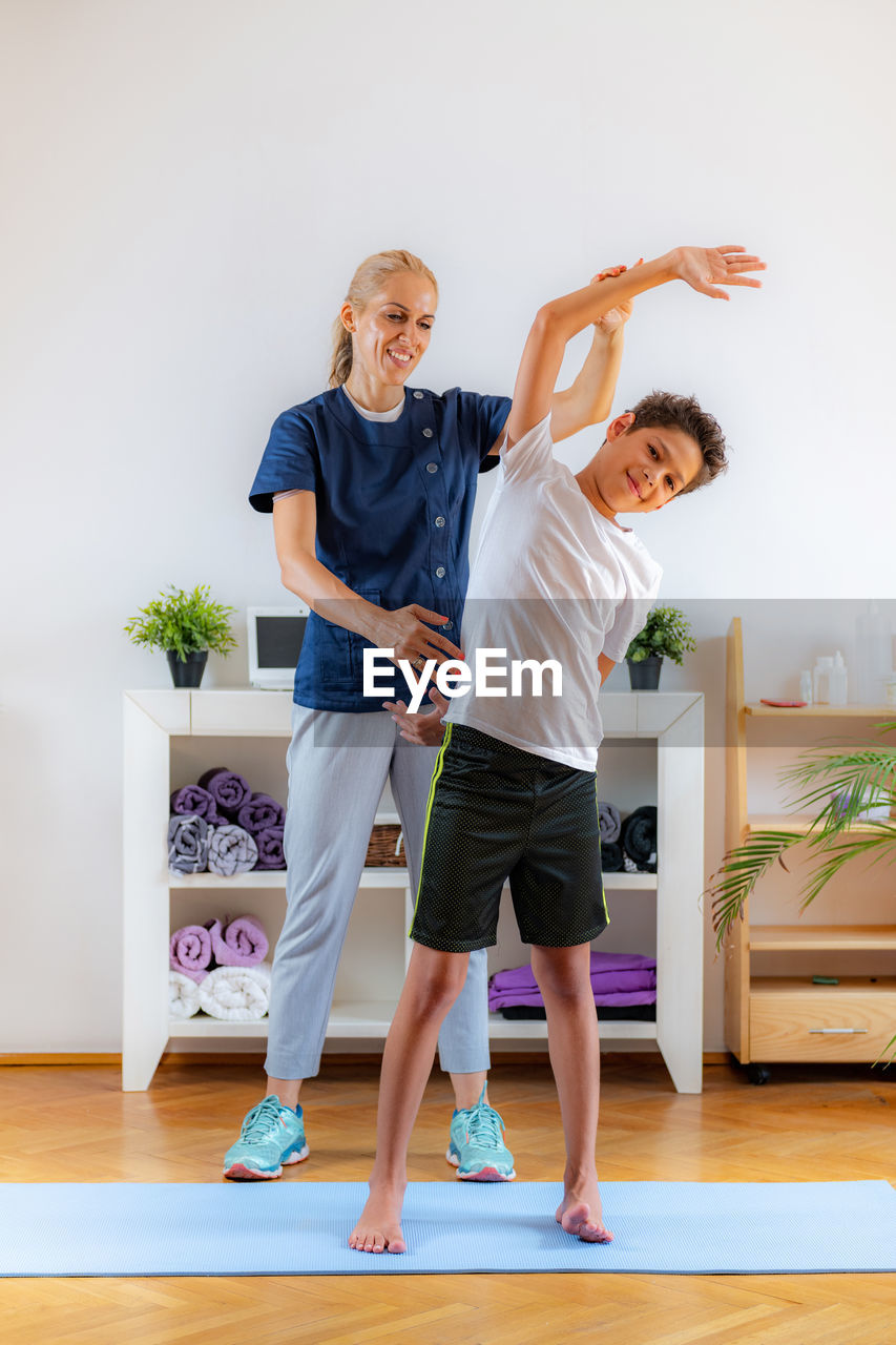 Lateral flexion exercise for children. boy exercising with physical therapist.