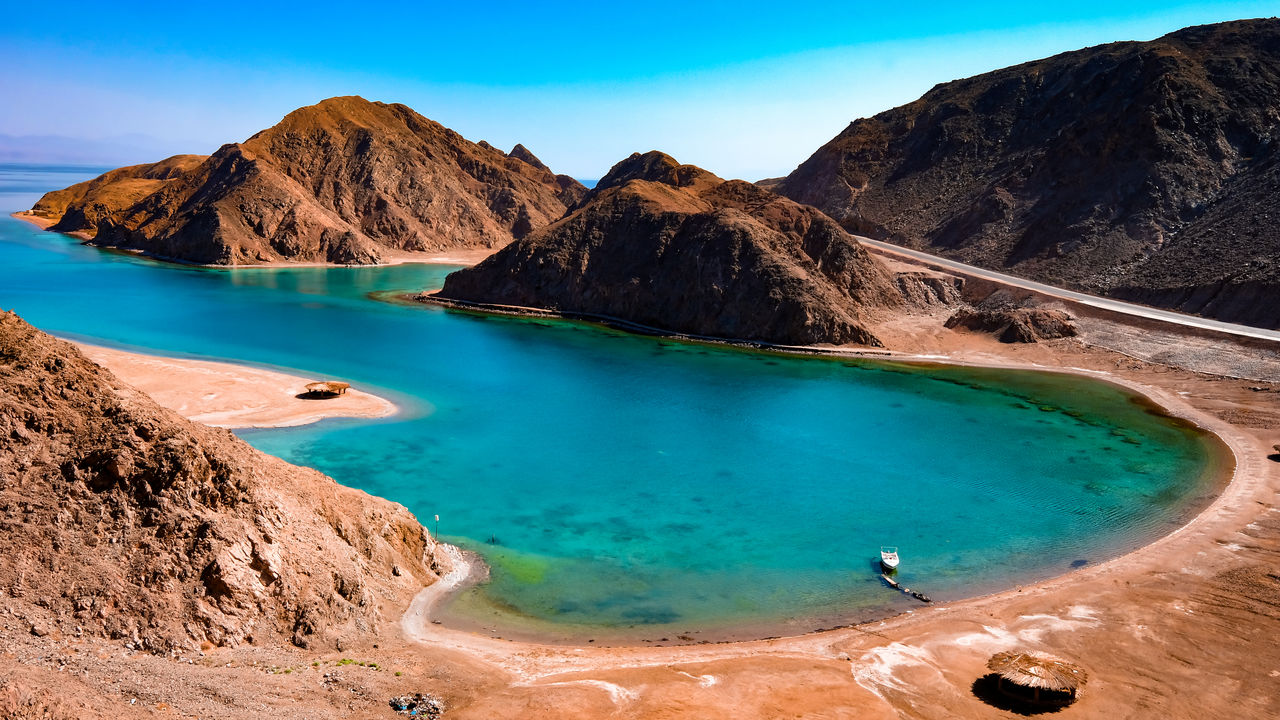 PANORAMIC VIEW OF SEA AND MOUNTAINS AGAINST BLUE SKY