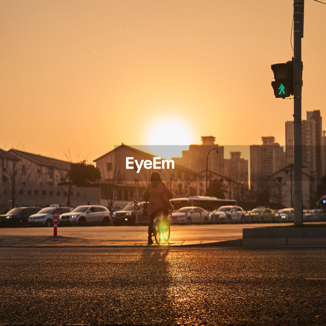 Cars on road at sunset while pedestrian trying to cross the road in bicycle i. sunset