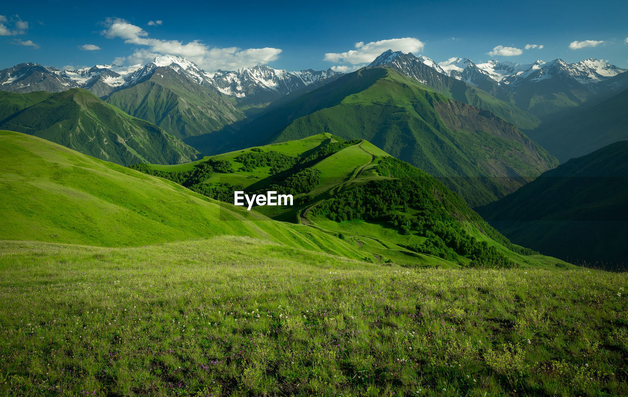 Beautiful green mountains with snowy peaks. scenic view of green mountains against sky
