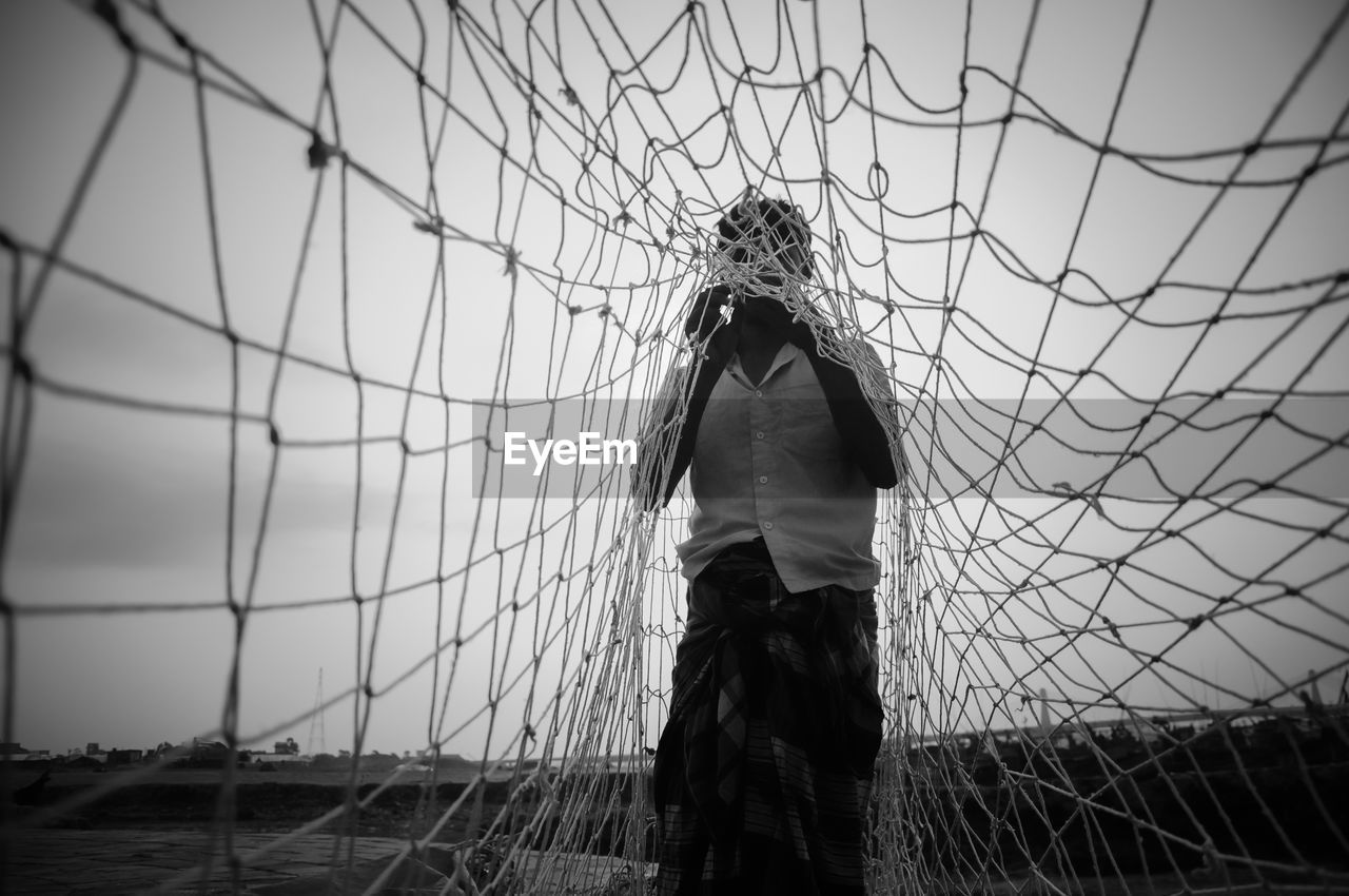 Man standing with fishing net against sky
