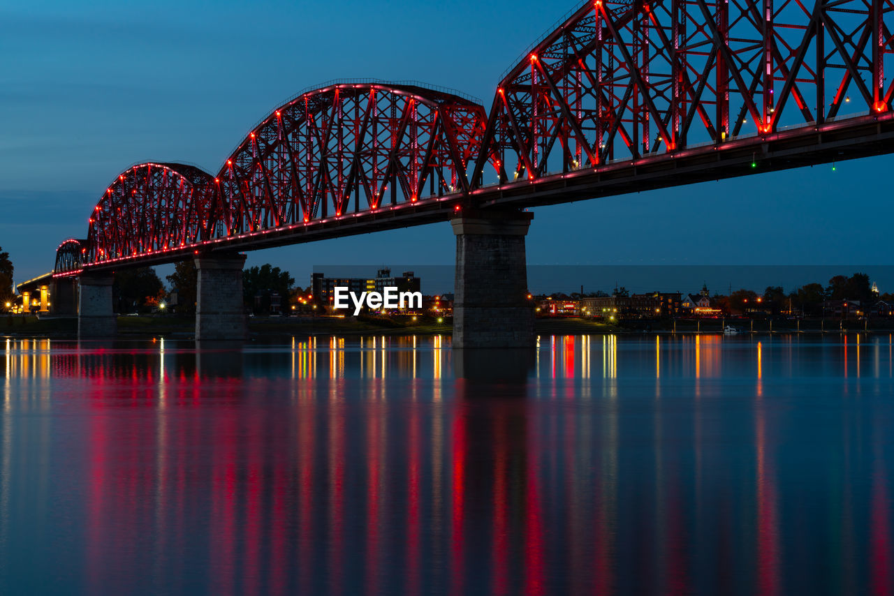 Illuminated bridge over river at night