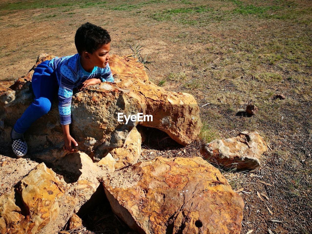 High angle view of boy sitting on rocks at field