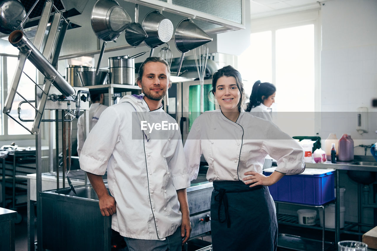 Portrait of confident chefs standing in commercial kitchen
