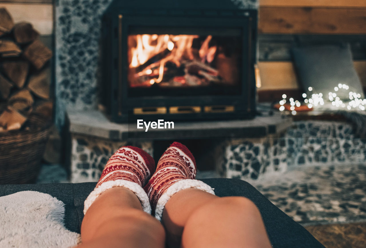 Personal perspective of woman relaxing on sofa by fireplace. warm christmas socks.