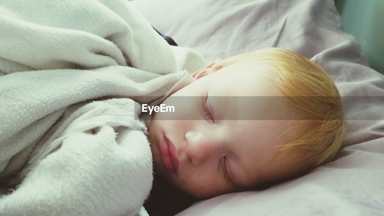 Close-up of cute boy sleeping on bed