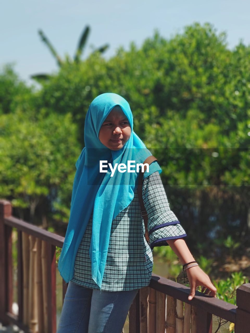 Teenage girl wearing hijab while leaning on railing