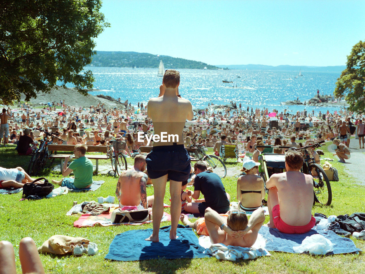 PEOPLE SITTING AT BEACH AGAINST SKY