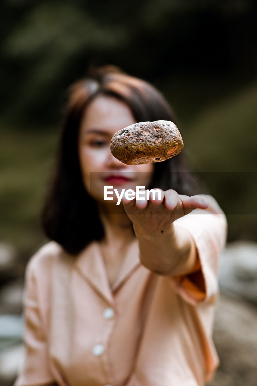 Close-up of woman throwing potato in air outdoors