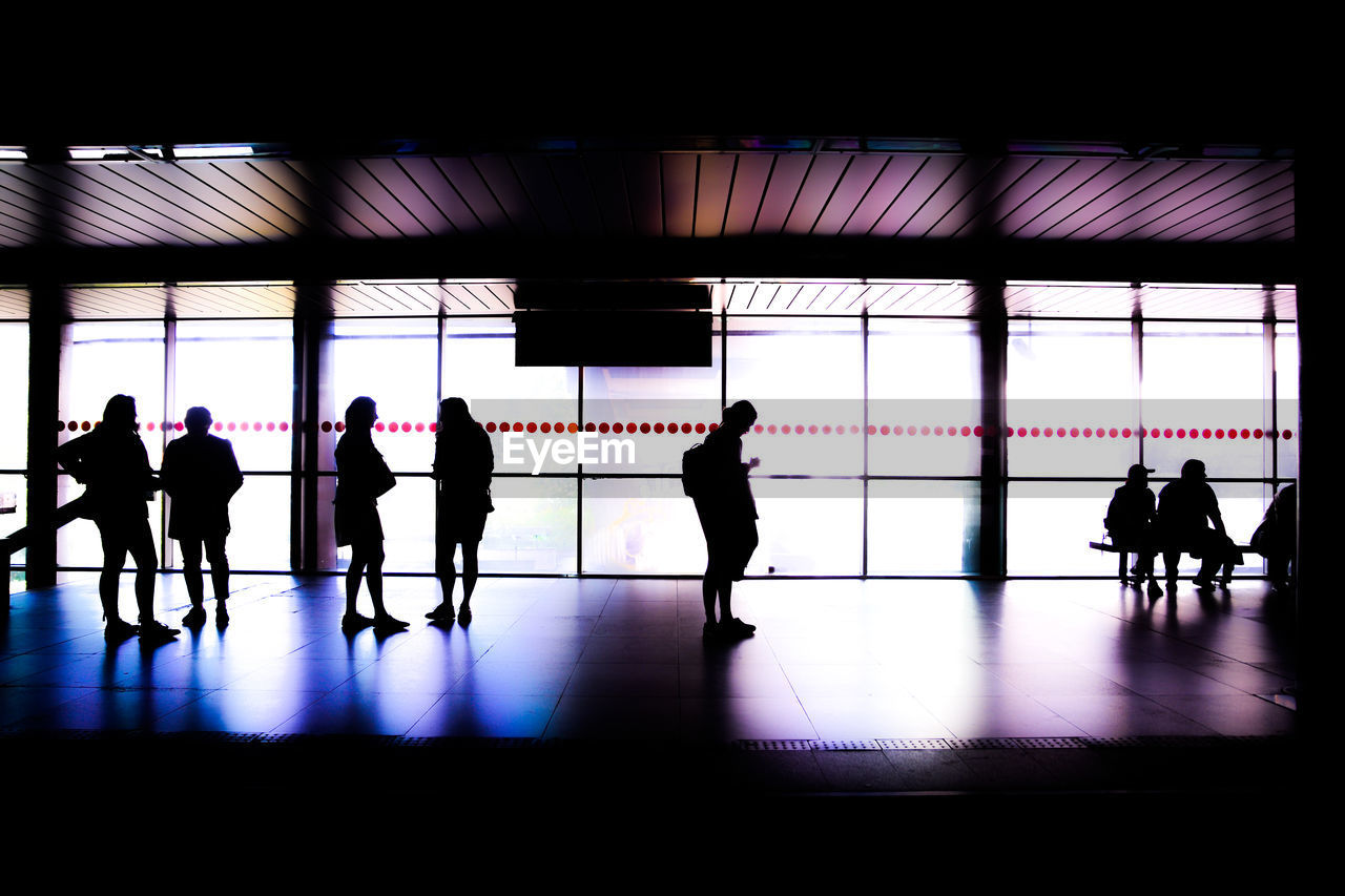 SILHOUETTE PEOPLE WALKING IN AIRPORT LOBBY