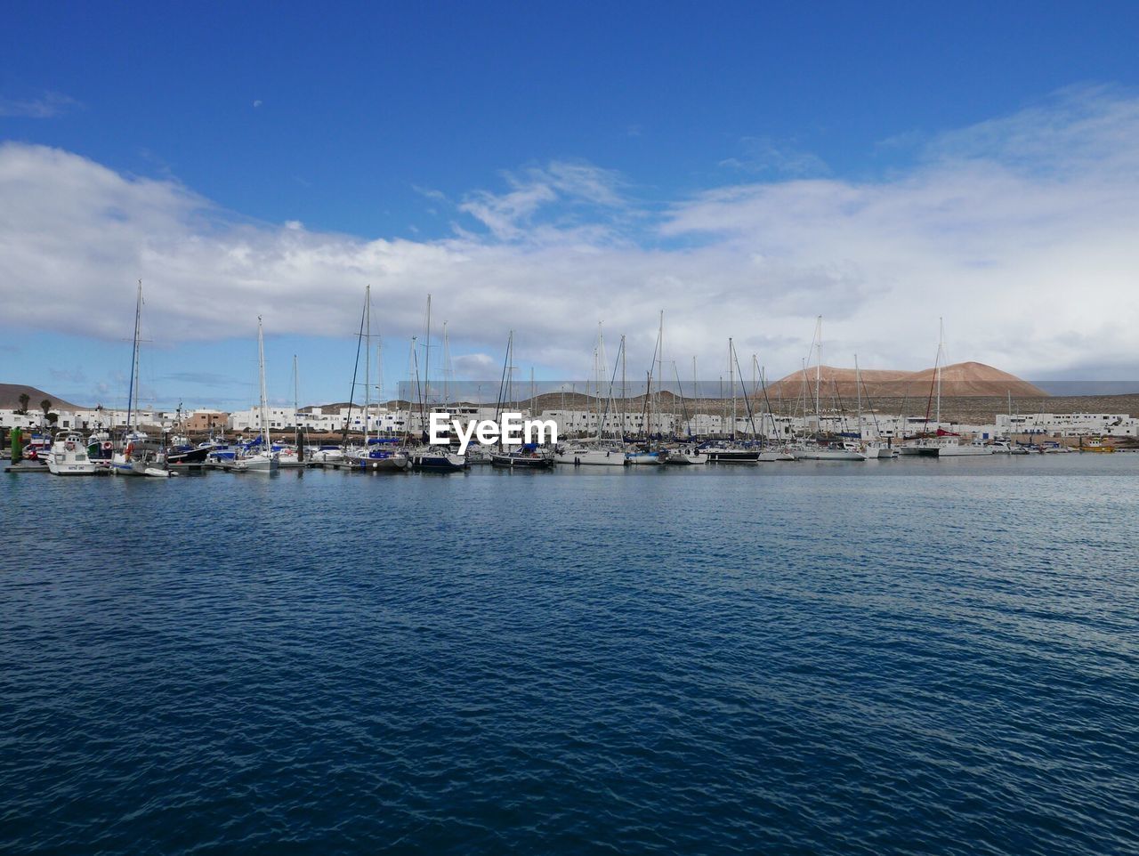 Boats in sea against cloudy sky