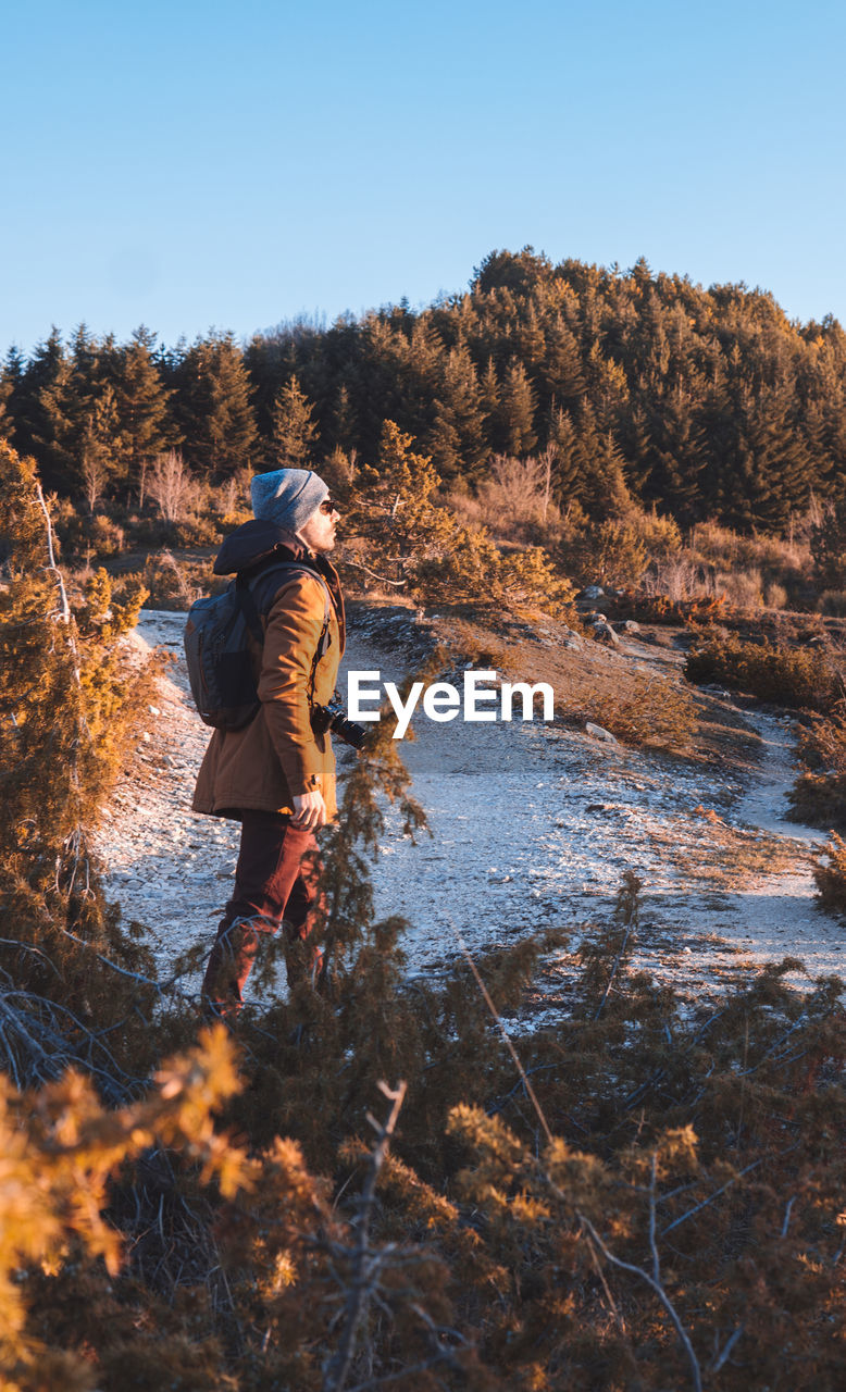 Side view of mid adult man standing by river in forest