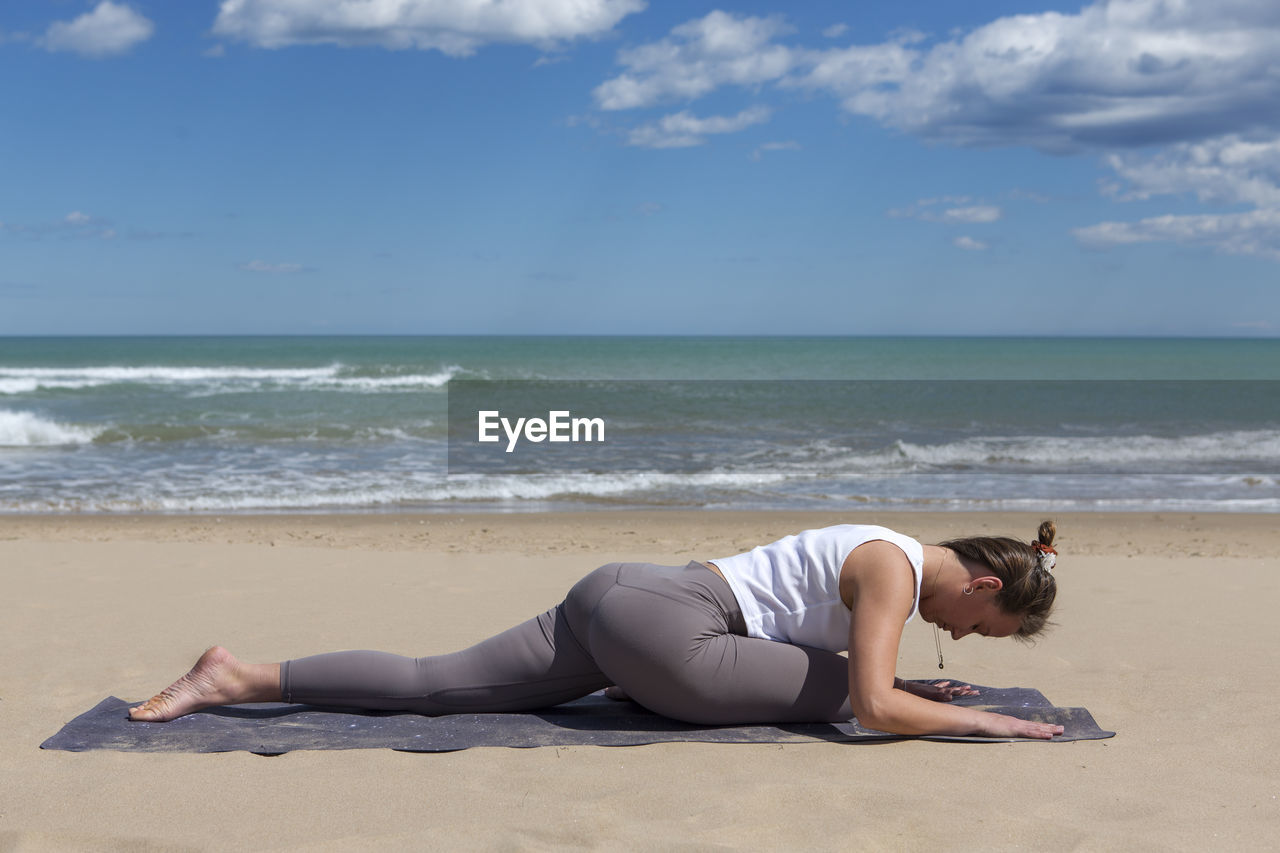 Sportswoman performing pilates exercises on the beach