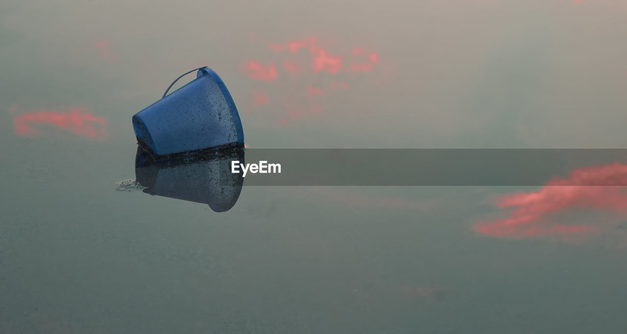 Close-up of bucket floating on lake during sunset