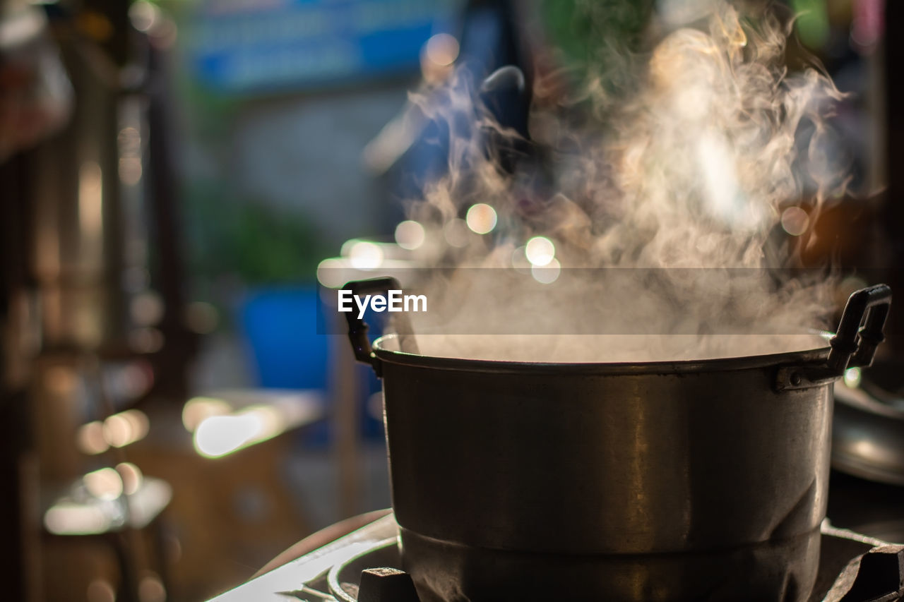 Metal pot boil soup on gas stove with smoke in thai kitchen. make food for breakfast.